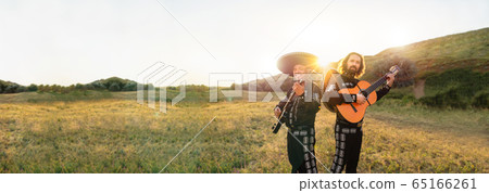 Mexican musicians mariachi on the background of field and mountains at sunset. 65166261