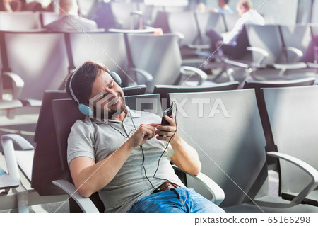 Portrait of man using smartphone with headphones 65166298