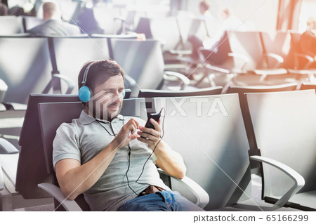 Portrait of man using smartphone with headphones 65166299