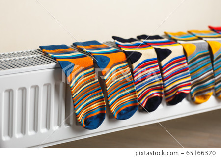 colorful socks are being drying on the radiator 65166370