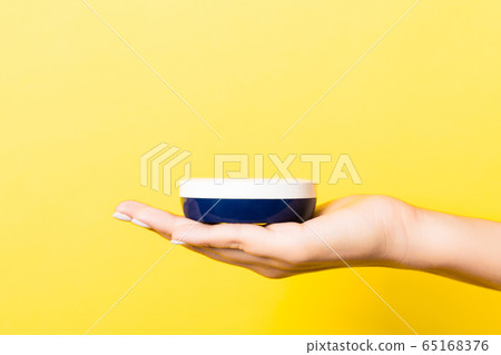 Yellow background with woman's hand holding a 65168376