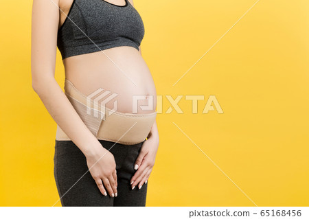 Close up of pregnant woman with supporting bandage Close up of pregnant woman with supporting bandage 65168456