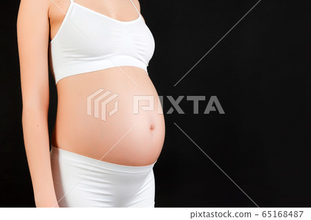 Cropped image of pregnant woman's abdomen at black Cropped image of pregnant woman's abdomen at black 65168487