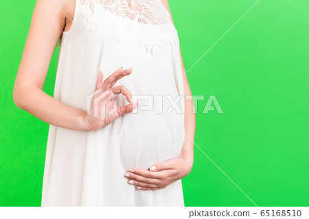 Close up of happy pregnant woman in white dress Close up of happy pregnant woman in white dress 65168510