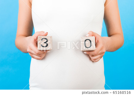 Cropped portrait of pregnant woman holding cubes Cropped portrait of pregnant woman holding cubes 65168516