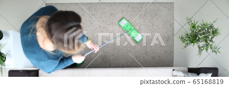 Girl carefully mops floor in apartment, top view 65168819