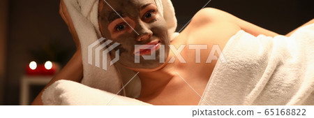 Girl with towel on her head and mud mask her face 65168822