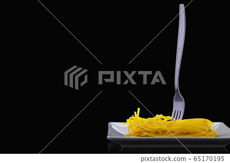 Stainless fork and tagliatelle pasta on the white 65170195