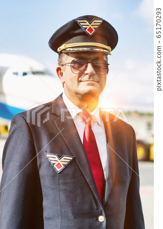 Portrait of mature pilot standing against airplane 65170293
