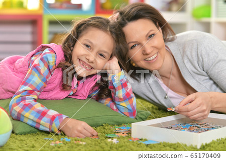 Close up portrait of mother with little daughter collecting puzzle 65170409