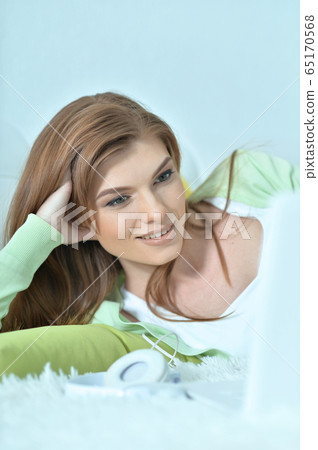 Portrait of young woman using laptop at home Portrait of young woman using laptop at home 65170568