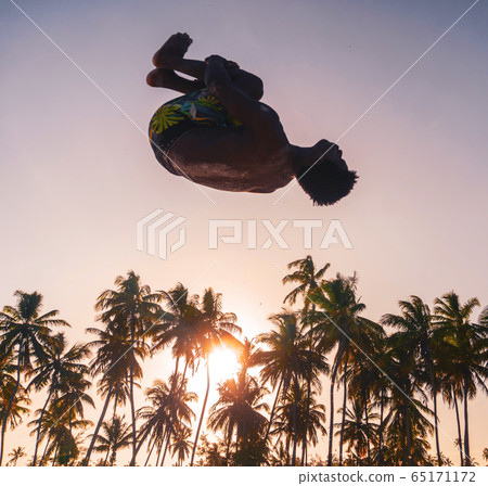 Young Attractive Muscular and Strong Athletic Black African Man at the White Sand Beach Training Acrobatics and Jumping Gymnastics Beach Performance 65171172