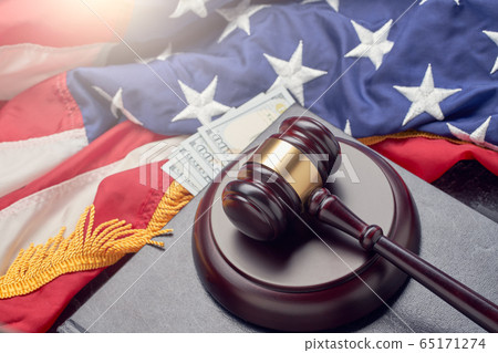 Wooden judge gavel, banknotes on background of American flag on black surface 65171274