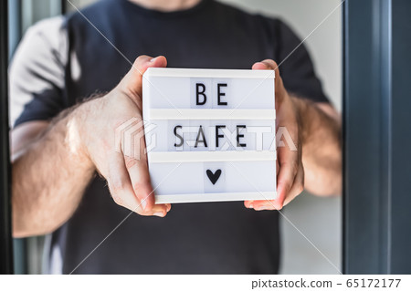 Man holding lightbox with text Be safe in his hand Man holding lightbox with text Be safe in his hand 65172177