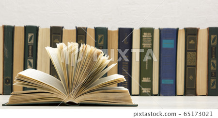 Composition with vintage old hardback books, diary, fanned pages on wooden deck table and abstract background. Books stacking. Back to school. Copy Space. Education background. Composition with vintage old hardback books, diary, fanned pages on wooden deck table and abstract background. Books stacking. Back to school. Copy Space. Education background. 65173021