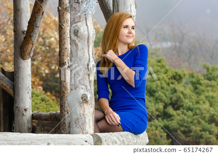 Beautiful girl in bright blue dress sits on a Beautiful girl in bright blue dress sits on a 65174267