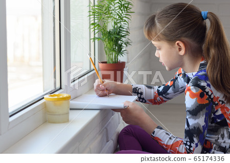 The child draws with a pencil on the windowsill at 65174336