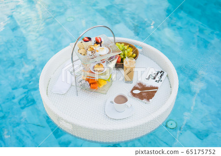 Breakfast and afternoon tea set floating around swimming pool Breakfast and afternoon tea set floating around swimming pool 65175752