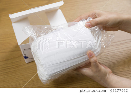 Female hand to take out the mask from the box and check Female hand to take out the mask from the box and check 65177922