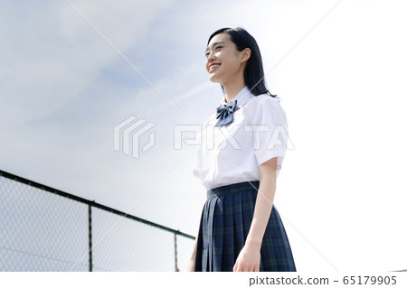 Schoolgirl looking up at the sky on the roof 65179905