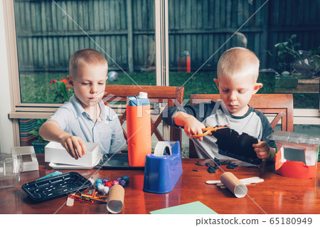 Kids making crafts from different recycled materials on desk. Kids making crafts from different recycled materials on desk. 65180949
