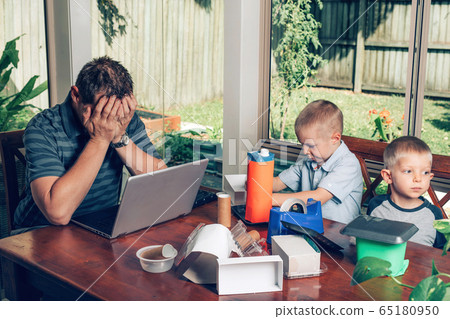 Father trying to work on the Internet on a laptop while kids making crafts from recycled materials. Father trying to work on the Internet on a laptop while kids making crafts from recycled materials. 65180950