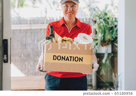 Delivery woman in protective gloves delivers paper bag with food products. Delivery woman in protective gloves delivers paper bag with food products. 65180956