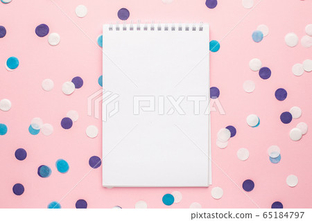 Notebook and blue, white and lilac confetti on pink color paper background minimal style 65184797
