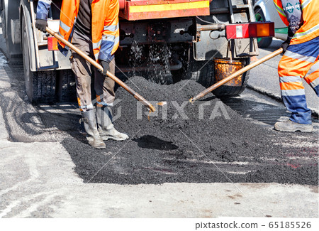 A team of road workers patches part of the road 65185526