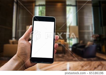 A man hand holding smart phone device in the bright office room interior. A man hand holding smart phone device in the bright office room interior. 65186196