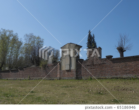 old red brick wall of country cemetery at village Cvikov in luzicke hory, Lusatian Mountains, early spring, blue sky 65186946