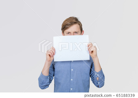 Serious Teenage boy holding blank sheet of paper 65188339