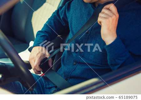 Close up man driver fastening seat belt. Guy 65189075