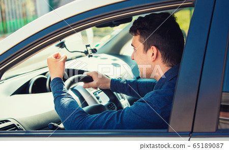 Young man driver yelling and shaking his fist 65189087