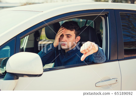 Exhausted young man sitting behind the steering 65189092