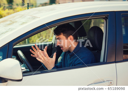 Angry man driving a vehicle arguing and gesturing Angry man driving a vehicle arguing and gesturing 65189098