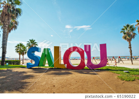 SALOU, SPAIN, AUGUST 23, 2018: Big word Salou varicolored sign at the Llevant Beach in Salou, Spain. Salou is the main place of European tourism SALOU, SPAIN, AUGUST 23, 2018: Big word Salou varicolored sign at the Llevant Beach in Salou, Spain. Salou is the main place of European tourism 65190022