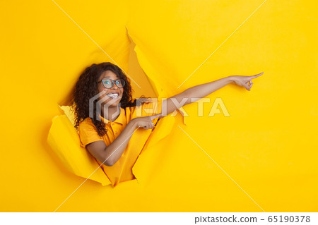 Young woman posing over yellow background. Emotional female