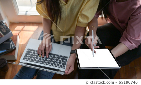 Two female college students use a tablet and a Two female college students use a tablet and a 65190746