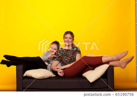 beautiful girl and wjman lies on a black sofa in homemade clothes with pillows beautiful girl and wjman lies on a black sofa in homemade clothes with pillows 65190756