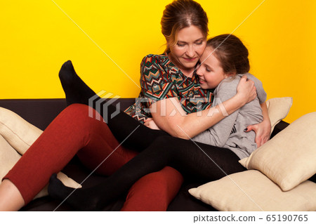 beautiful girl and wjman lies on a black sofa in homemade clothes with pillows 65190765