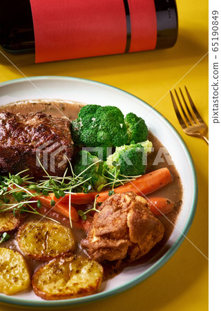 Rare roast beef meal with organic root vegetables and traditional Yorkshire pudding with sauce, stewed vegetables. 65190849