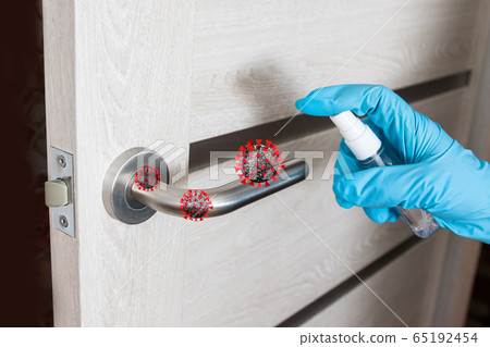 Cleaner hand in a medical latesky glove holds a bottle with an antiseptic sticks on the metal door handle in a clinic or public room to protect against germs, viruses and dirt Cleaner hand in a medical latesky glove holds a bottle with an antiseptic sticks on the metal door handle in a clinic or public room to protect against germs, viruses and dirt 65192454
