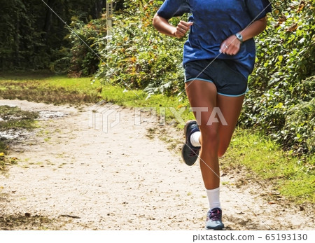 Female running on dirt path trail alone 65193130