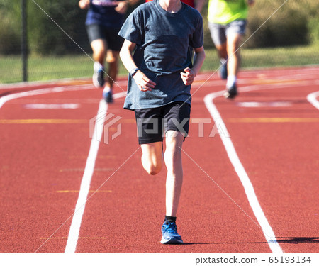 Front view of runner running in a lane on a track Front view of runner running in a lane on a track 65193134