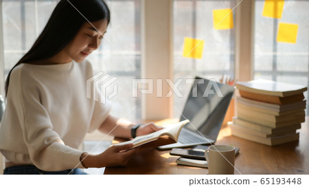 Asian teenage girl reading a book to prepare for 65193448