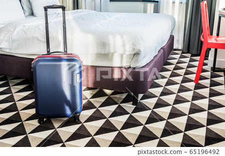 suitcase stands by the bed in the hotel room 65196492