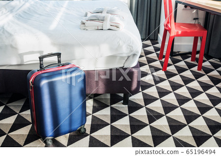 suitcase stands by the bed in the hotel room 65196494