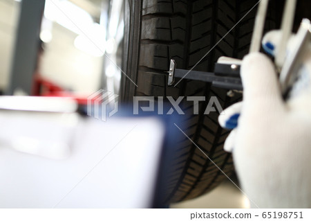 Mechanic holding tool hand that measures tire wear 65198751