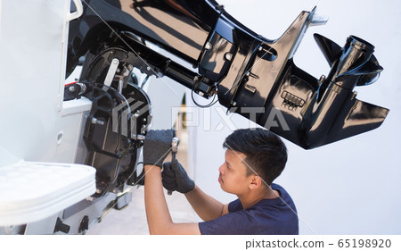Mechanic is installing speed boat engine 65198920